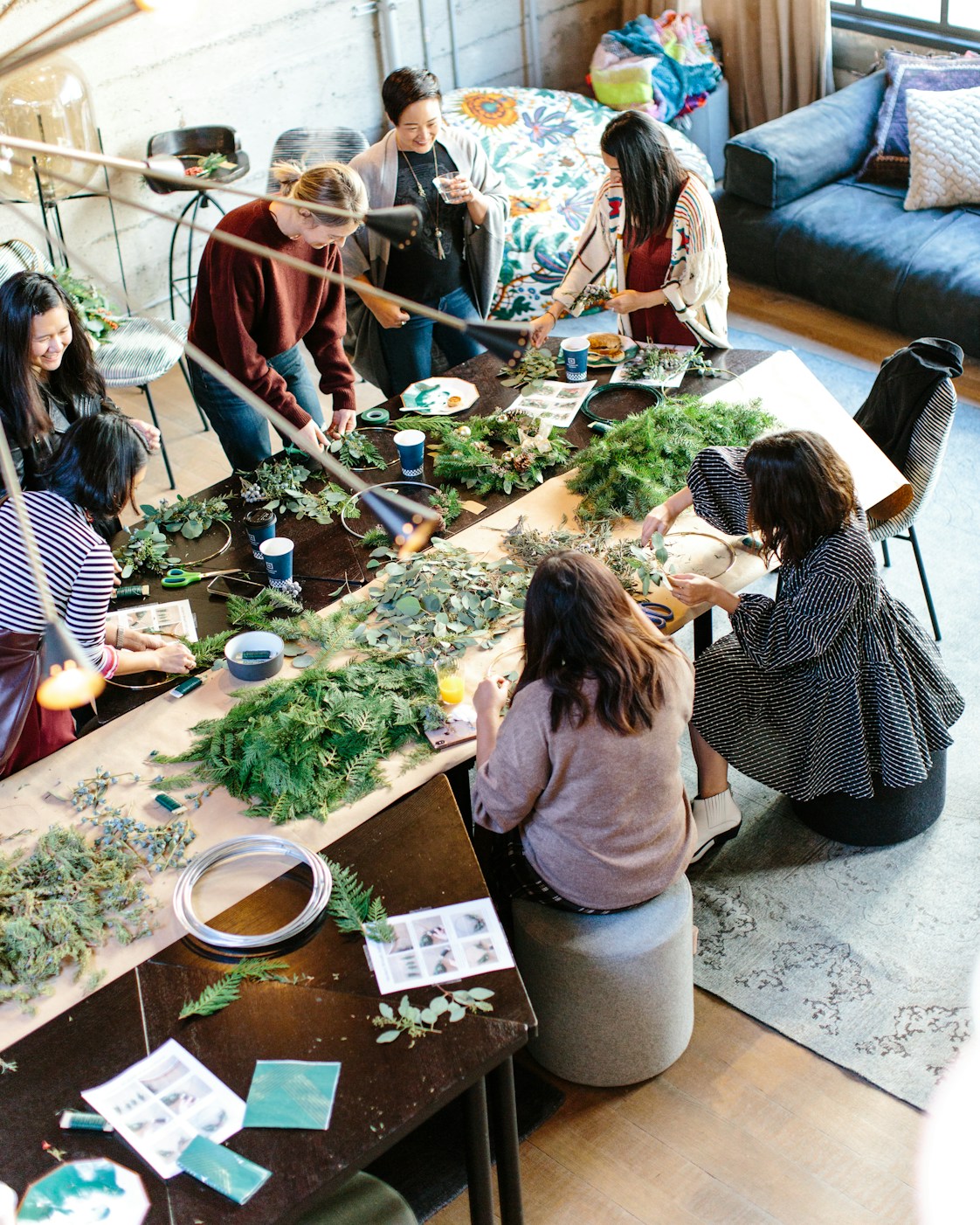Members crafting with greenery around a sunlit workshop table