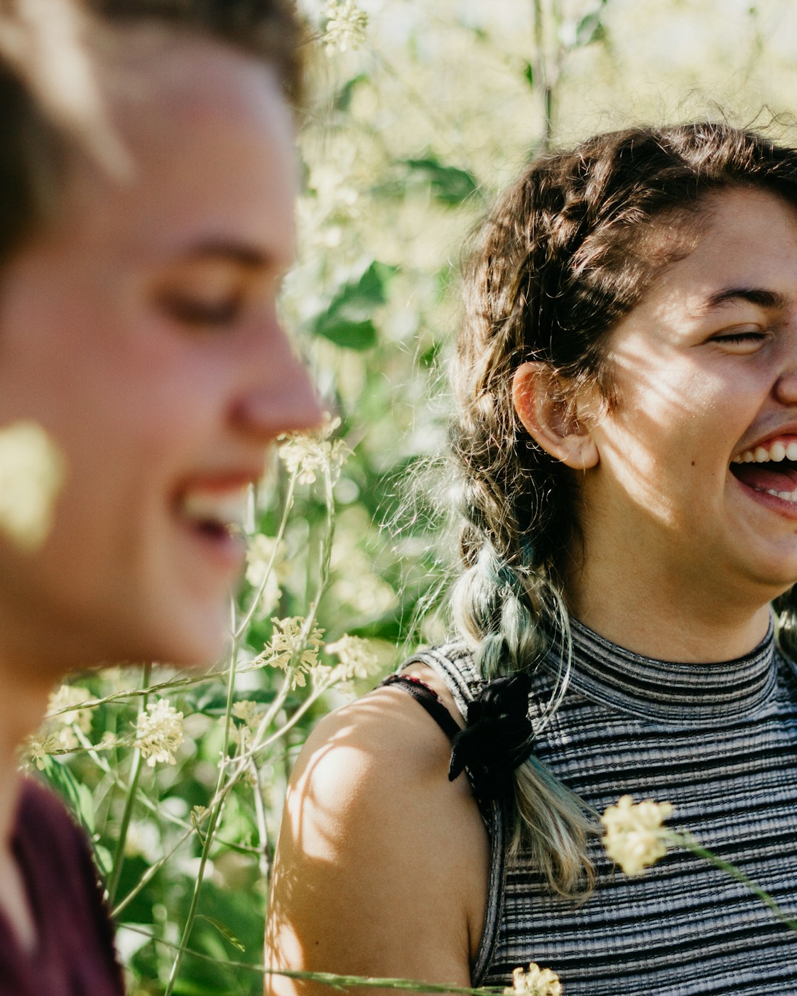 Two friends laughing together in a sunny meadow